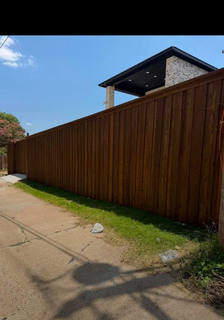 Fence staining in progress — spray application
